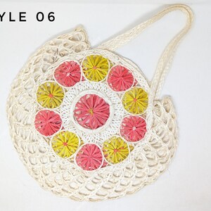 Pu&ograve; includere: Una borsa tote rotonda in tessuto color bianco sporco etichettata STYLE 06. La borsa presenta un pannello centrale circolare decorato con un motivo di fiori radiali alternati gialli e rosa, circondato da una struttura a rete aperta e manici.