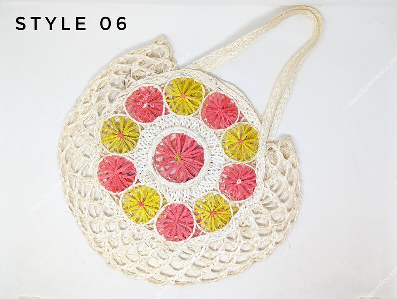 Pu&ograve; includere: Una borsa tote rotonda in tessuto color bianco sporco etichettata STYLE 06. La borsa presenta un pannello centrale circolare decorato con un motivo di fiori radiali alternati gialli e rosa, circondato da una struttura a rete aperta e manici.