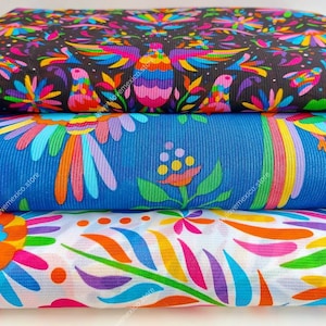 May include: Three folded pieces of fabric stacked vertically. The top layer is black with a colorful bird and floral pattern. The middle layer is blue with a bird and floral design. The bottom layer is white with a vibrant, multi-colored floral print.