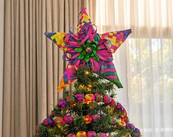 May include: A five-pointed star tree topper made of woven palm leaves in vibrant shades of pink, yellow, blue, and green. The center features a decorative bow made of matching colorful ribbons. Small woven spheres in the same colors adorn the tree.