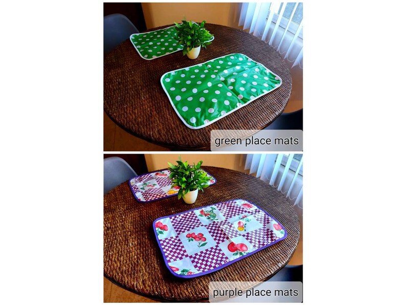 May include: Two placemats on a table. One placemat is green with white polka dots and the other is white with a purple border and a red and green fruit pattern. The text "green place mats" and "purple place mats" is below each placemat.