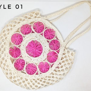 Pu&ograve; includere: Una borsa a rete rotonda color bianco sporco con due lunghi manici e un pannello circolare centrale decorato con accenti floreali a forma di stella di colore rosa acceso. Il testo STYLE 01 &egrave; stampato in nero nell'angolo in alto a sinistra.