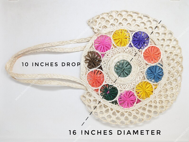 Pu&ograve; includere: Una borsa tote rotonda in tessuto color crema con un motivo circolare centrale circondato da colorati accenti di filato a forma di stella in rosa, giallo, viola, arancione, blu, verde e marrone. Ha un manico di 25,4 cm e un diametro di 40,6 cm.