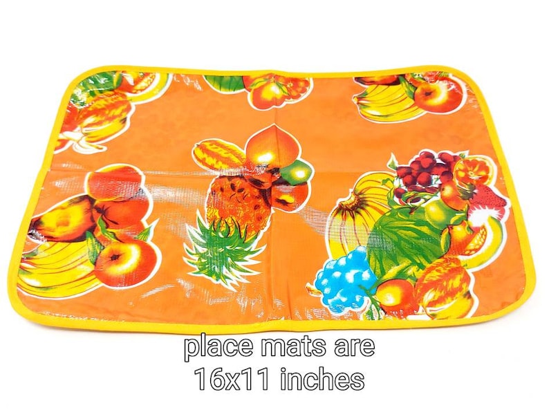 May include: Orange place mat with a yellow border and a colorful fruit design. The place mat is 16x11 inches.