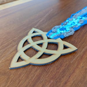 Op de afbeelding: Een houten bladwijzer met een Keltisch knoop en een blauwe en grijze garen kwast.