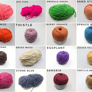 May include: A collection of sixteen yarn balls in various colors including coral, hot pink, emerald green, sand stone, fire orange, thistle, burnt orange, spruce blue, hickory brown, dried moss, eggplant, laguna yellow, rouge, stone blue, sangria, and tortilla brown.