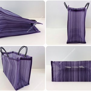 May include: A rectangular tote bag featuring a purple and white vertical striped pattern. The bag is constructed from a semi-transparent mesh material and includes two black handles attached to the top edge. The text ilovemexico.store is visible.