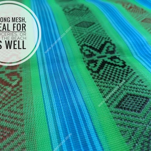May include: A green and blue mesh fabric featuring vertical stripes and woven geometric patterns in black and dark red. The text on the fabric reads: STRONG MESH, IDEAL FOR GROCERIES, OR FOR THE BEACH AS WELL. The material has a visible grid texture.