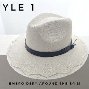 May include: A cream-colored fedora hat featuring a black leather band around the crown and a scalloped edge with embroidery around the brim. The text STYLE 1 and EMBROIDERY AROUND THE BRIM are visible in the image.