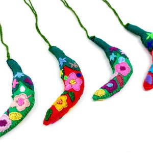 May include: Four handmade felt chili pepper decorations with colourful embroidered flowers. Each ornament has a green stem and a loop for hanging.