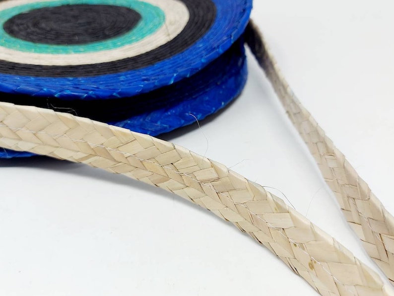 May include: A woven straw bag with a blue, black, and white striped pattern. The bag has a woven straw strap.