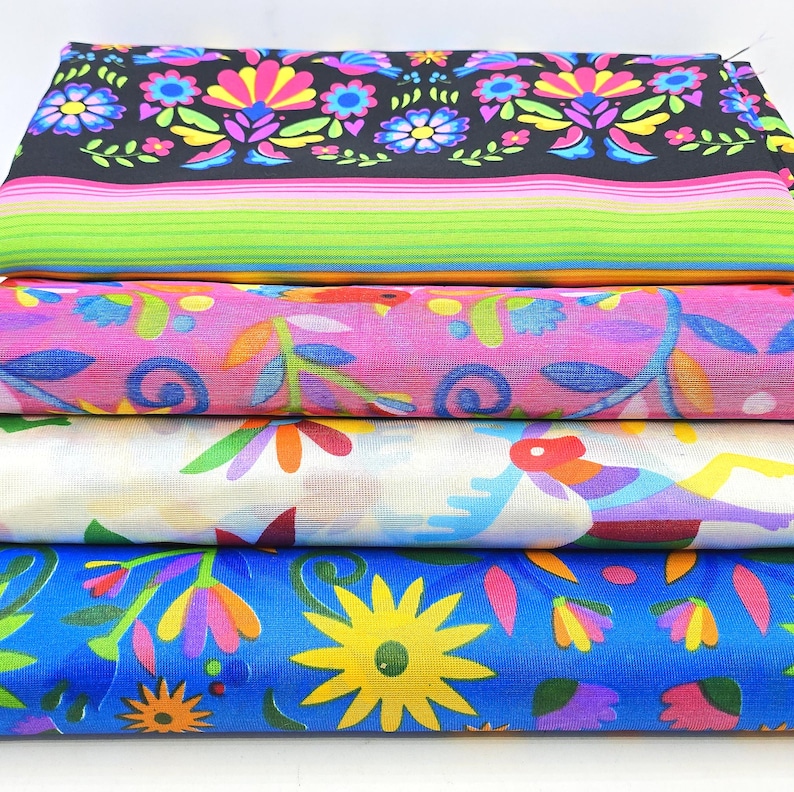 May include: A stack of four folded fabric pieces. The top piece is black with colorful floral patterns and horizontal stripes. The second is pink with floral motifs. The third is white with colorful animal and leaf prints. The bottom is blue with yellow flowers.