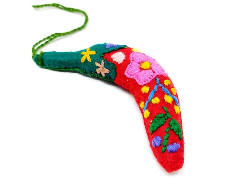 May include: A red felt boomerang with colourful embroidered flowers and leaves. The boomerang has a green felt loop at the top for hanging.