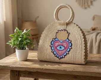 Bolso de mano de paja de palma natural con parche de corazón bordado.