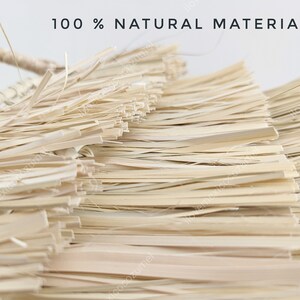 Może przedstawiać: Pleciony przedmiot wykonany z jasnobeżowych, suszonych wł&oacute;kien roślinnych ułożonych w warstwowe, płaskie paski. Napis 100 % NATURAL MATERIALS jest wydrukowany na czarno u g&oacute;ry. Konstrukcja posiada pleciony uchwyt wystający z lewej strony.
