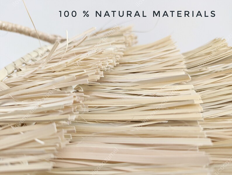 Może przedstawiać: Pleciony przedmiot wykonany z jasnobeżowych, suszonych wł&oacute;kien roślinnych ułożonych w warstwowe, płaskie paski. Napis 100 % NATURAL MATERIALS jest wydrukowany na czarno u g&oacute;ry. Konstrukcja posiada pleciony uchwyt wystający z lewej strony.