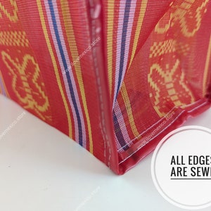 May include: A red woven plastic bag featuring a repeating yellow butterfly pattern and vertical stripes in blue, purple, and white. The bag has reinforced red stitched edges and a circular white graphic with the text ALL EDGES ARE SEWN.