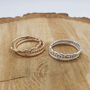 May include: Two sets of stacking rings, one set in gold and one set in silver. Each set has three rings with different textures.