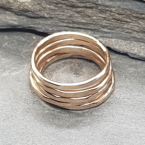 May include: A set of four gold-toned stacking rings. The rings are made of a hammered metal and have a slightly irregular shape.