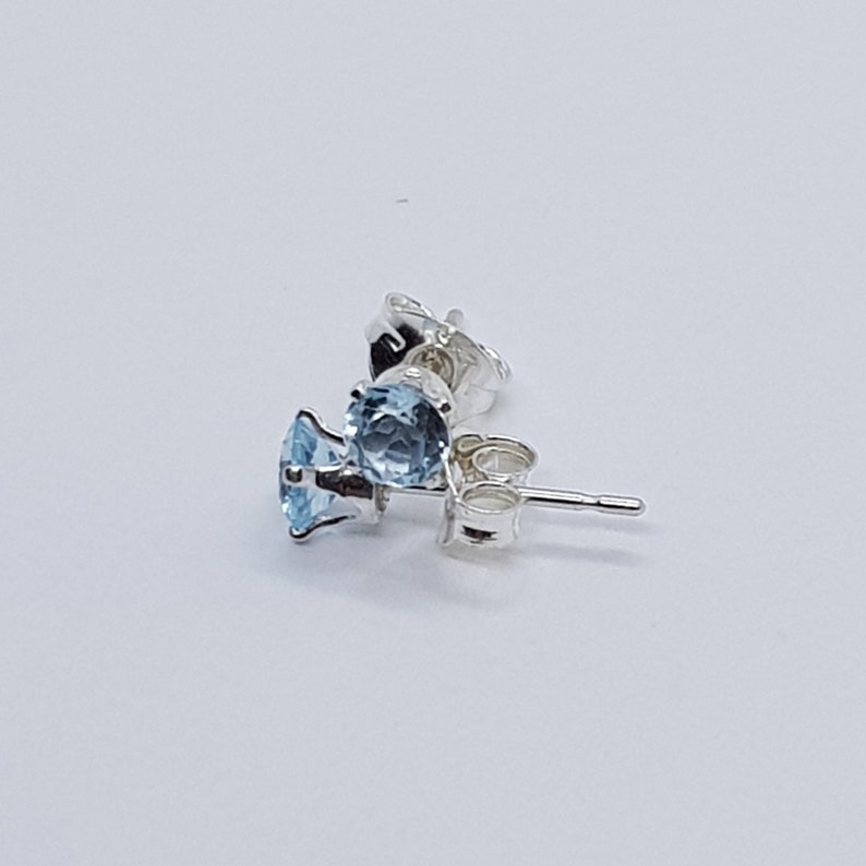 May include: Silver stud earrings with a light blue gemstone.