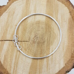 May include: A silver bangle bracelet with a twisted detail at the clasp.