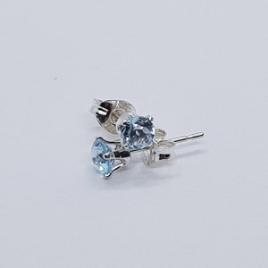 May include: A pair of silver stud earrings with light blue round gemstones.