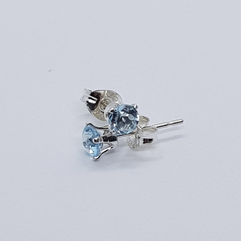 May include: A pair of silver stud earrings with light blue round gemstones.