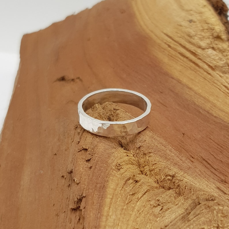 May include: A silver hammered band ring on a wooden surface.
