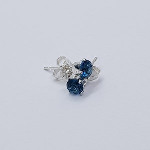 May include: A pair of silver stud earrings with blue gemstones.