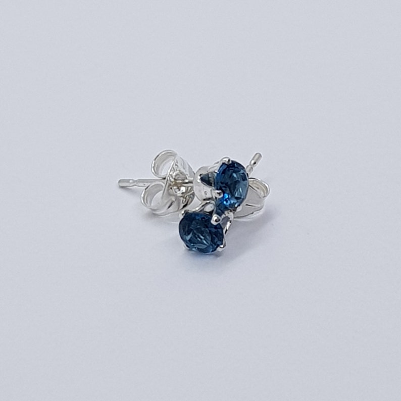 May include: A pair of silver stud earrings with blue gemstones.