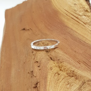 May include: A silver ring with a hammered texture. The ring is simple and delicate, and it would make a great everyday piece of jewelry.