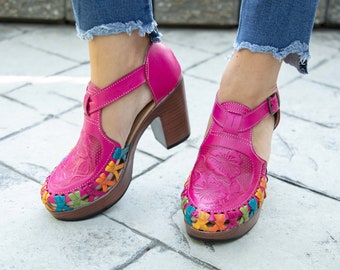May include: Pink leather heeled sandals with colorful embroidery and a cutout design.