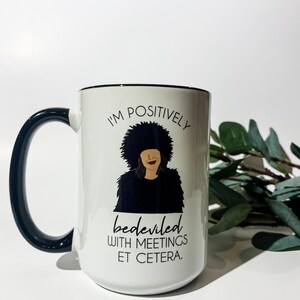 Puede incluir: Taza de cer&aacute;mica blanca con asa y borde negros. La taza presenta una ilustraci&oacute;n en blanco y negro de una persona con una cita que dice "Estoy positivamente atormentado con reuniones etc."