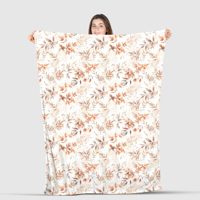 May include: A white fleece blanket with a repeating pattern of brown and orange watercolor leaves.