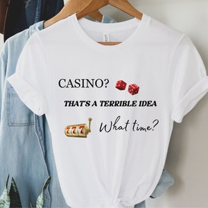 May include: White t-shirt with the text "CASINO? THAT'S A TERRIBLE IDEA What time?" and a graphic of dice and a slot machine.