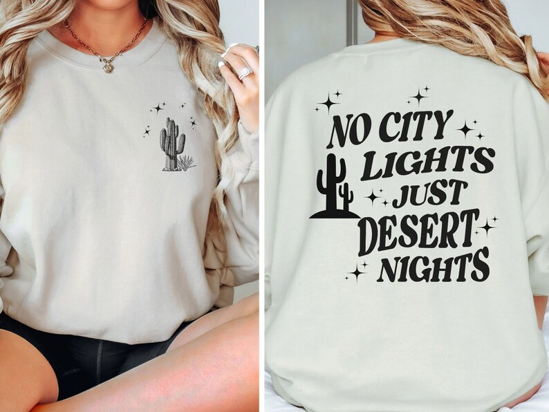 Może przedstawiać: Jasnobeżowa bluza z nadrukiem kaktusa i gwiazd na przodzie i napisem "NO CITY LIGHTS JUST DESERT NIGHTS" na plecach.