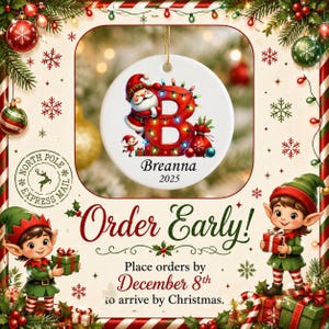 May include: A round white ceramic Christmas ornament featuring a large red letter B decorated with colorful string lights, a cartoon Santa Claus, and a gift sack. The name Breanna and the year 2025 are printed in black text below the letter.