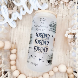 May include: A white frosted glass jar with a wooden lid and black lettering. The jar has inspirational quotes and scripture verses, including "Forever he is glorified", "Forever he is lifted high", "Forever he is risen", and "Created with a purpose".
