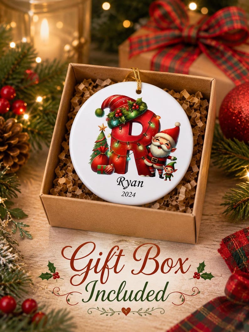 May include: A round white ceramic Christmas ornament featuring a large red letter R decorated with green holly, a small Christmas tree, and a cheerful Santa Claus figure. The name Ryan and the year 2024 are printed in black below the letter R.