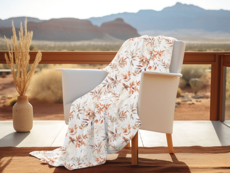 May include: A white chair with a throw blanket featuring a brown and white floral pattern. The chair is on a patio with a view of a desert landscape.