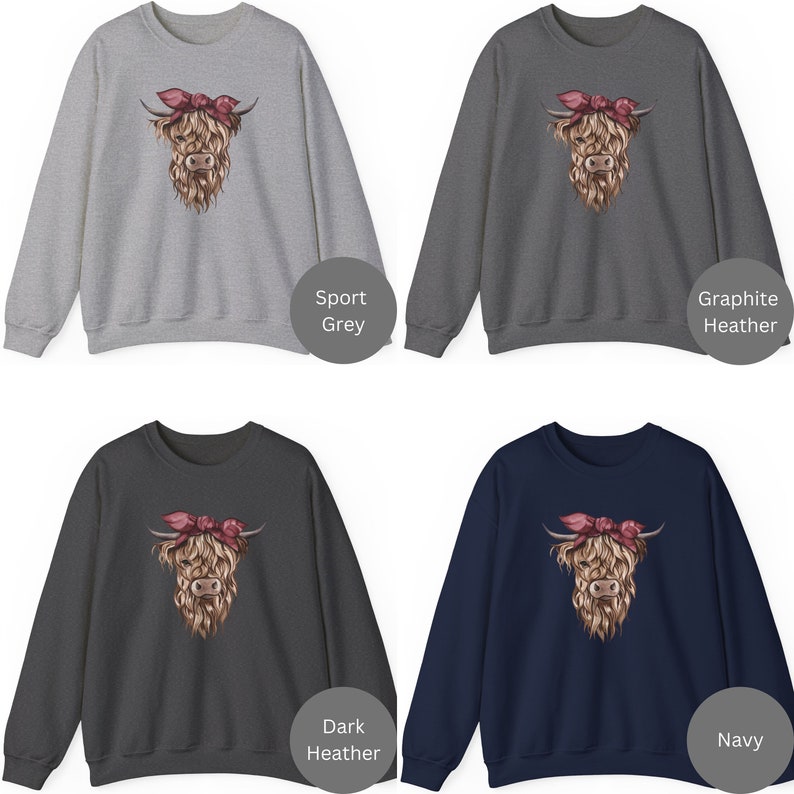 May include: Four sweatshirts in sport grey, graphite heather, dark heather, and navy. Each features a detailed illustration of a Highland cow with a pink bandana. The cow's fur is a mix of brown and tan, with a pink bandana.