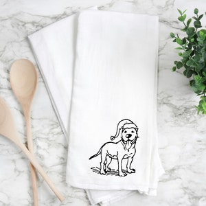 May include: White kitchen towel with a black and white illustration of a dog wearing a Santa hat.