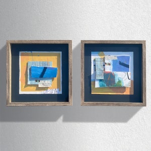Pode incluir: Duas peças de arte abstrata emolduradas com um esquema de cores amarelo, azul e branco. As peças são emolduradas em uma moldura de madeira escura.