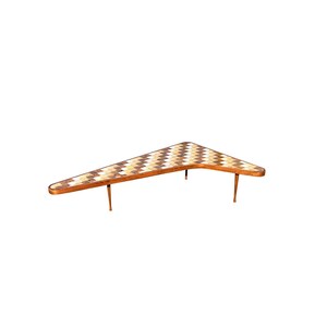 May include: A boomerang-shaped coffee table with a geometric pattern of brown, white, and beige tiles. The table has three legs made of metal.