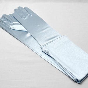 May include: A pair of long, light blue satin gloves. The gloves are folded in half and are lying on a white surface.