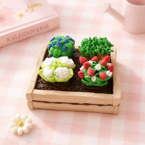 May include: A square wooden-textured planter box containing four miniature vegetable and fruit patches. The display features sculpted blue berries, green leafy vegetables, white cauliflower heads, and red strawberries set in dark brown soil.