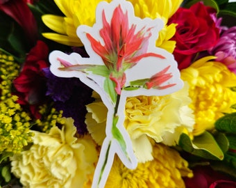 May include: A bouquet of flowers with a red and yellow flower sticker. The bouquet includes yellow chrysanthemums, red roses, yellow carnations, and red berries.