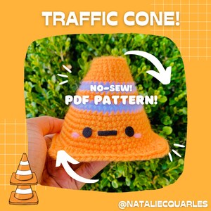 Puede incluir: Un juguete de cono de tráfico de crochet con una cara linda. El cono es naranja y blanco con una franja azul. El texto "NO-SEW! PDF PATTERN!" está escrito en el cono. El cono está sostenido en una mano contra un fondo verde de hojas.