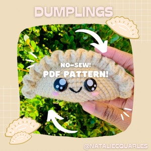 May include: A crocheted dumpling plush toy with a smiling face and big eyes. The toy is beige and has a ruffled edge. The text "NO-SEW! PDF PATTERN!" is written on the toy. The image is set against a background of green foliage.