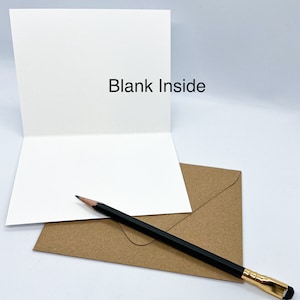 K&ouml;nnte beinhalten: Eine leere wei&szlig;e Karte mit einem braunen Umschlag und einem schwarzen Bleistift. Auf der Karte steht "Blank Inside".